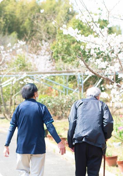 おじいさんとスタッフが散歩をしている